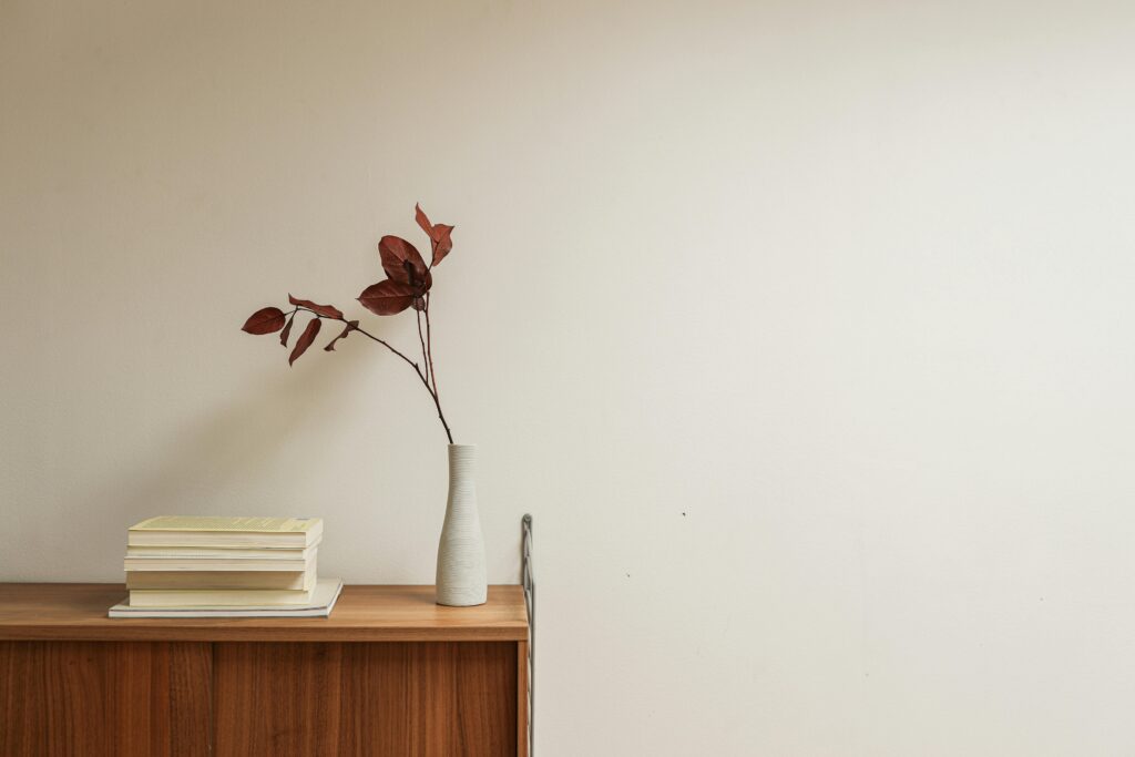 A minimalist interior shot showcasing a wooden table with books and a ceramic vase.