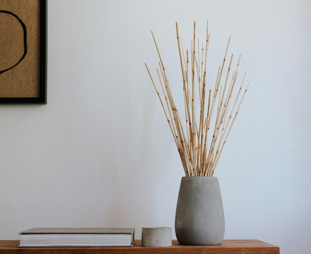 Minimalist Japandi decor featuring a ceramic vase with wooden sticks on a wooden table.